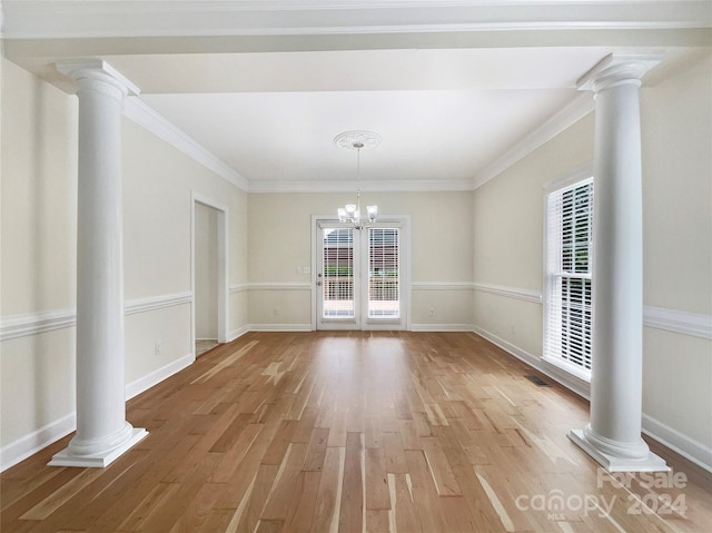 unfurnished dining area with decorative columns and hardwood / wood-style flooring