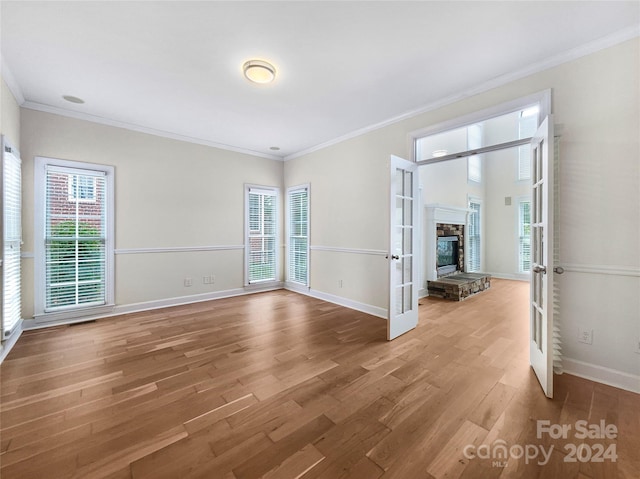 empty room with wood-type flooring, ornamental molding, and french doors