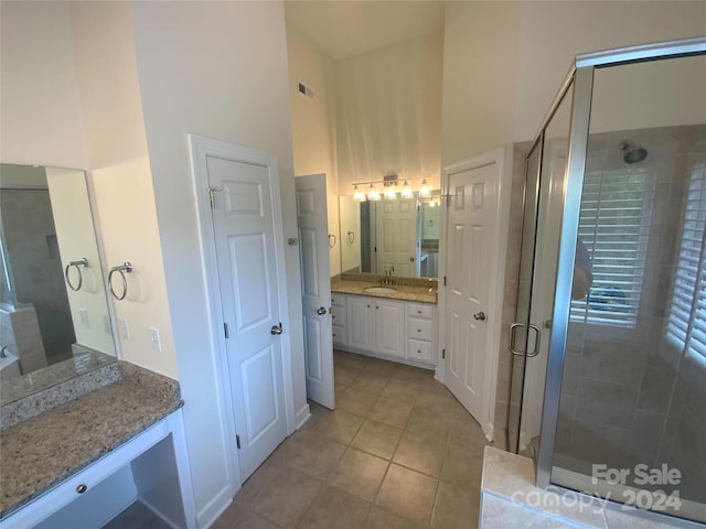 bathroom featuring tile patterned floors, vanity, a shower with door, and a towering ceiling