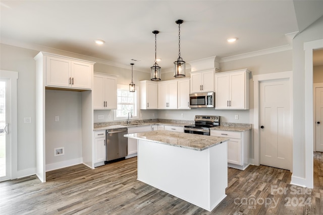 kitchen with pendant lighting, stainless steel appliances, a kitchen island, and white cabinetry