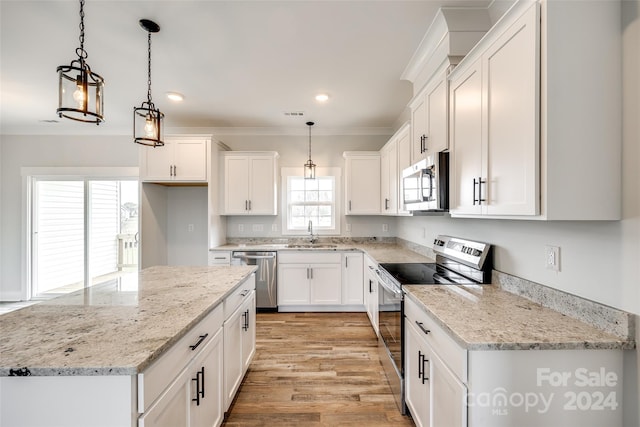 kitchen featuring white cabinets, appliances with stainless steel finishes, decorative light fixtures, and a wealth of natural light