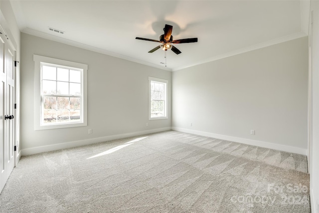 carpeted spare room featuring ceiling fan, plenty of natural light, and ornamental molding