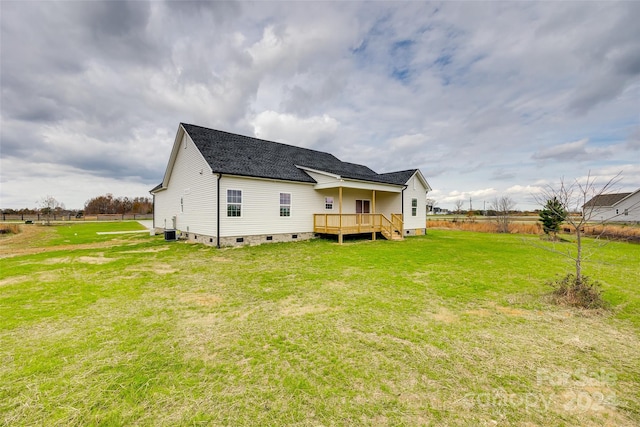 rear view of property with central AC, a deck, and a lawn