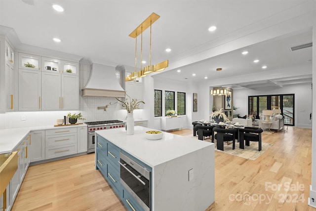 kitchen with appliances with stainless steel finishes, light hardwood / wood-style flooring, tasteful backsplash, pendant lighting, and custom exhaust hood