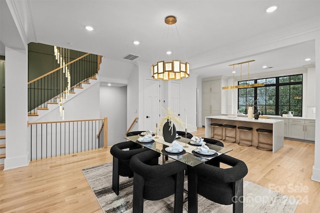 dining space with light wood-type flooring and ornamental molding