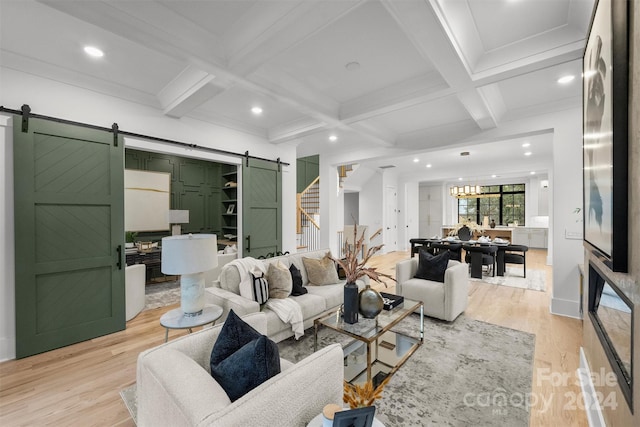 living room featuring light hardwood / wood-style floors, beamed ceiling, a barn door, and coffered ceiling