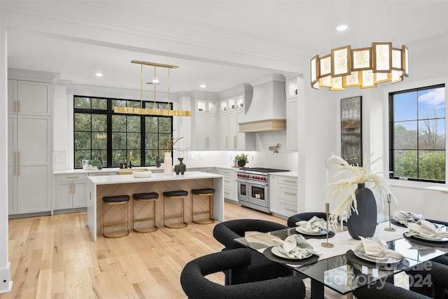 kitchen with pendant lighting, custom range hood, double oven range, and plenty of natural light