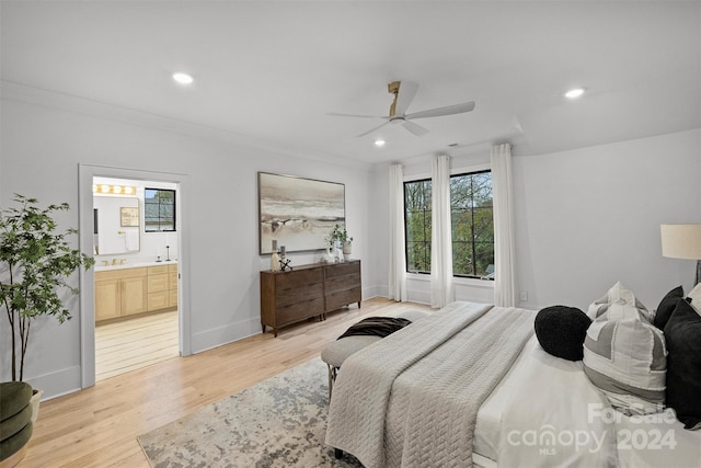 bedroom featuring ensuite bathroom, light hardwood / wood-style flooring, multiple windows, and ceiling fan