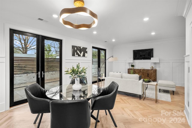 dining space with crown molding, french doors, and light parquet flooring