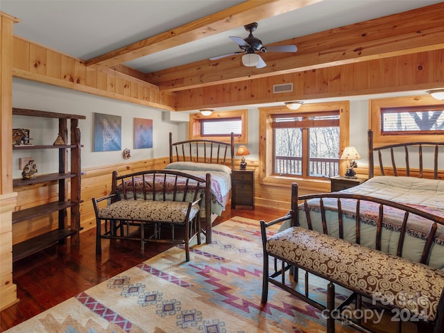 bedroom featuring ceiling fan, dark hardwood / wood-style floors, and wooden walls