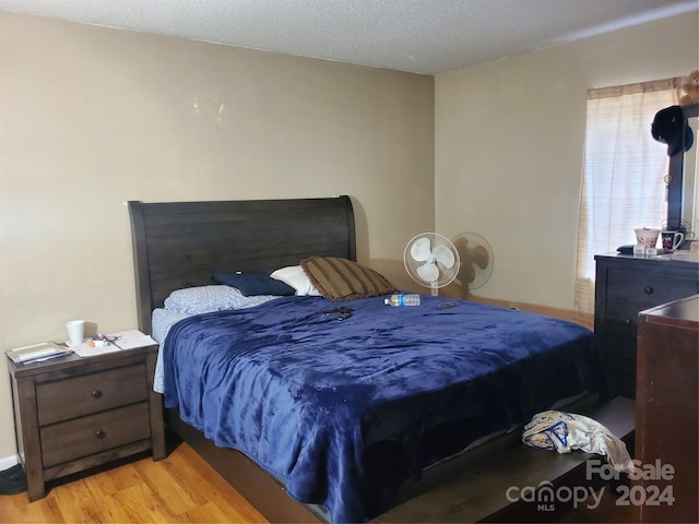 bedroom featuring light hardwood / wood-style floors and a textured ceiling