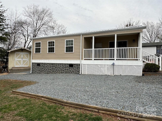 manufactured / mobile home featuring a porch and a storage shed