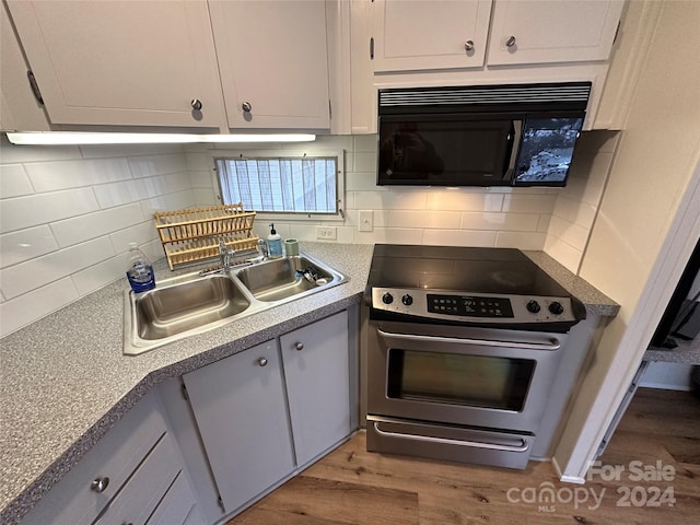 kitchen featuring hardwood / wood-style floors, backsplash, electric range, and sink