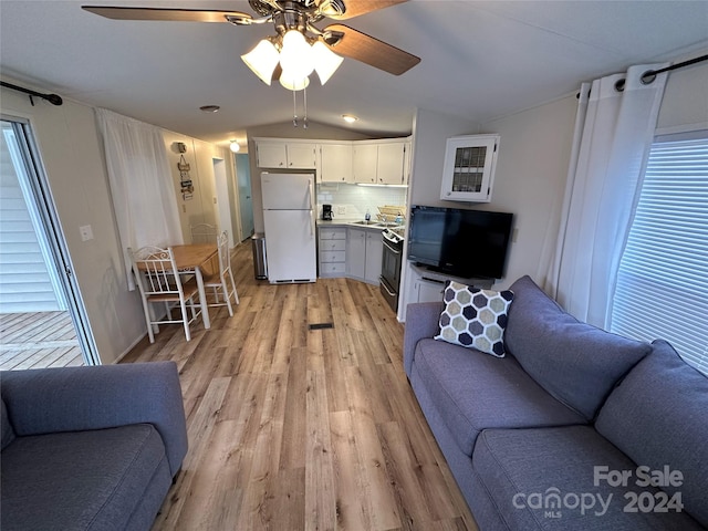 living room featuring ceiling fan, light hardwood / wood-style floors, and vaulted ceiling