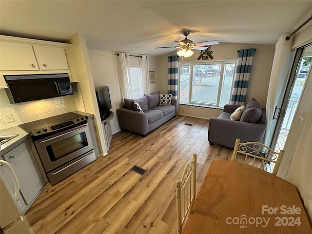 kitchen featuring ceiling fan, backsplash, stainless steel electric stove, light hardwood / wood-style flooring, and white cabinets