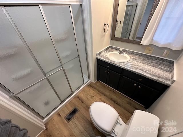 bathroom featuring vanity, hardwood / wood-style floors, toilet, and walk in shower