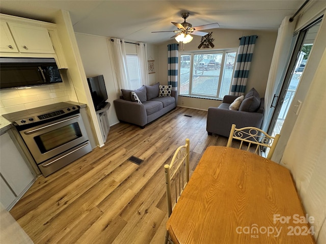 living room with vaulted ceiling, light hardwood / wood-style floors, and ceiling fan