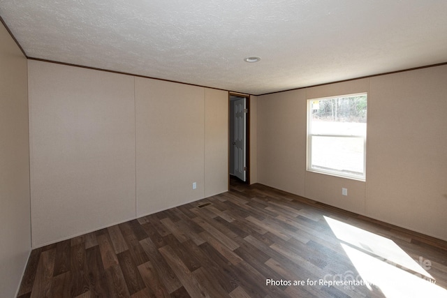 spare room featuring a textured ceiling and dark hardwood / wood-style flooring