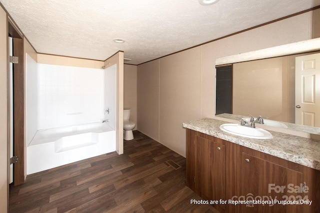 full bathroom featuring wood-type flooring, toilet, a textured ceiling, and oversized vanity