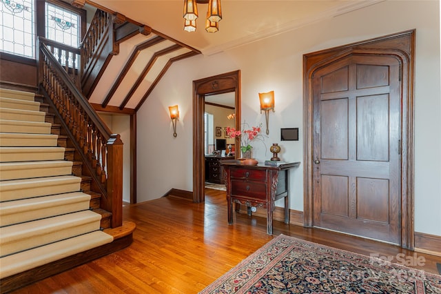 entryway with wood-type flooring and ornamental molding