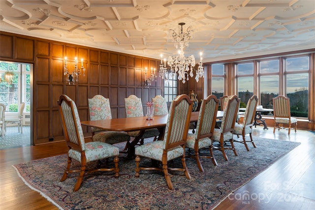 dining space featuring light wood-type flooring, wooden walls, an inviting chandelier, and ornamental molding