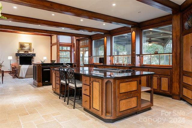 bar featuring ceiling fan, stainless steel gas cooktop, and beamed ceiling