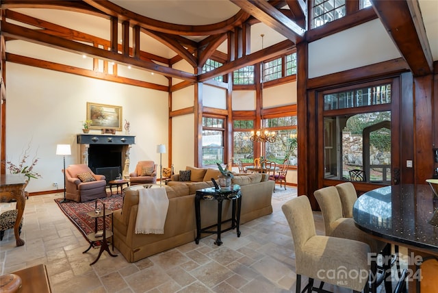 living room featuring a chandelier, a high ceiling, and a stone fireplace