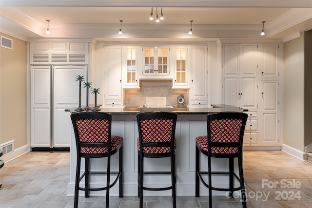 kitchen featuring a raised ceiling, a kitchen breakfast bar, white cabinetry, and a center island