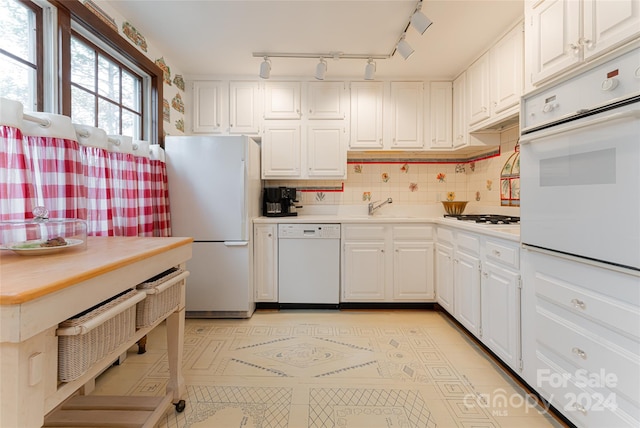 kitchen featuring tasteful backsplash, white cabinets, sink, and white appliances