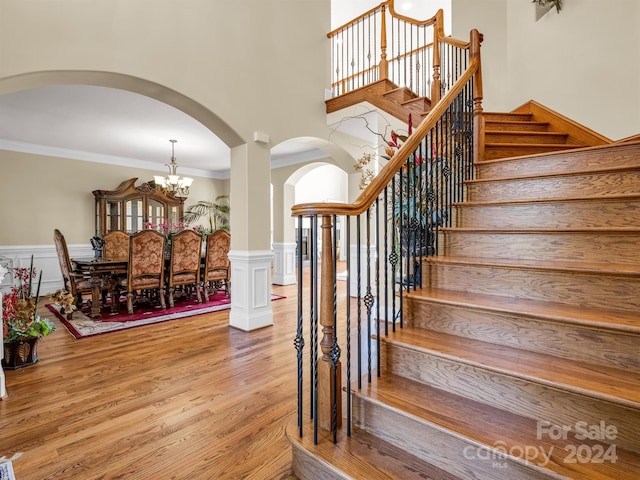 stairs with a chandelier, ornamental molding, and light hardwood / wood-style floors