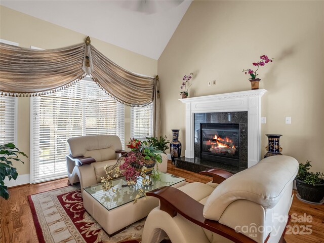 living room with hardwood / wood-style flooring, a premium fireplace, and vaulted ceiling