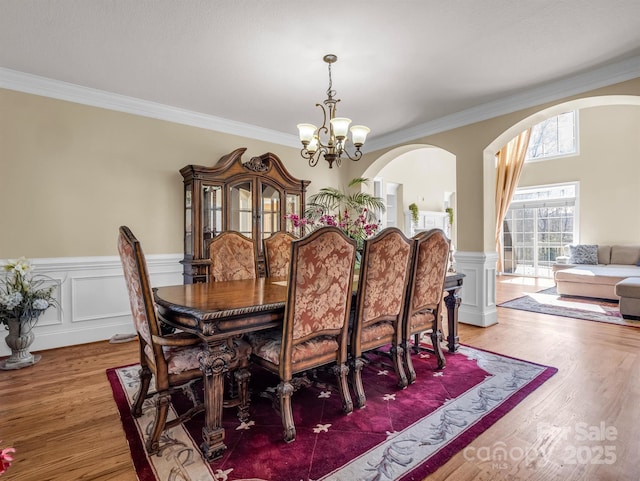 dining area with hardwood / wood-style flooring, crown molding, and a notable chandelier