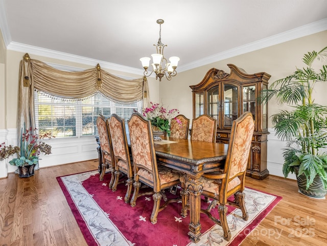 dining area with hardwood / wood-style flooring, crown molding, and a notable chandelier