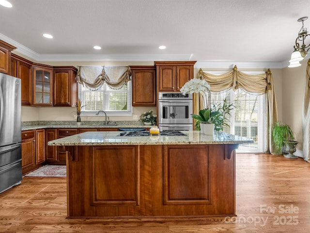 kitchen featuring stainless steel appliances, plenty of natural light, a center island, and light stone counters