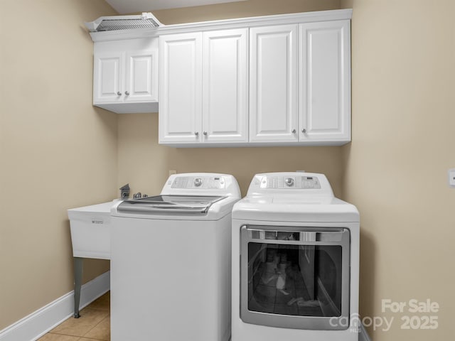 clothes washing area with cabinets, washer and dryer, and light tile patterned floors