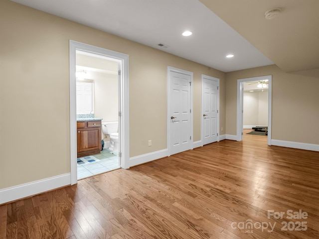 unfurnished bedroom featuring ensuite bathroom and light hardwood / wood-style floors