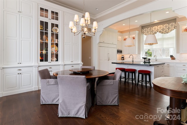 dining area with dark hardwood / wood-style flooring, a notable chandelier, sink, and crown molding