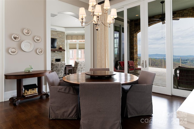 dining room with hardwood / wood-style flooring, crown molding, a chandelier, and a stone fireplace