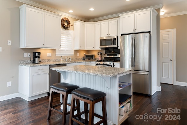 kitchen featuring dark hardwood / wood-style floors, a kitchen island, white cabinetry, appliances with stainless steel finishes, and crown molding