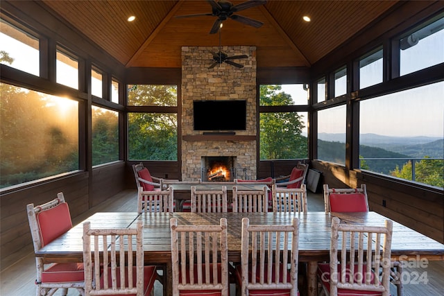 sunroom / solarium with ceiling fan, a fireplace, lofted ceiling, and wood ceiling