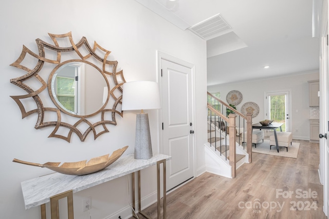 hall with crown molding and light hardwood / wood-style flooring