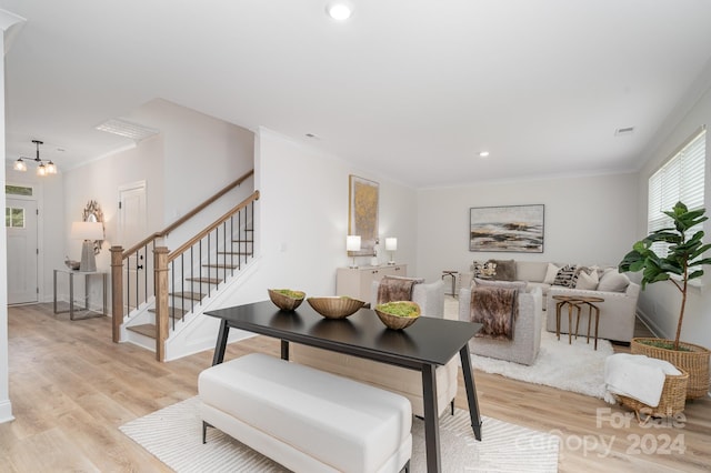 living room featuring an inviting chandelier, crown molding, and light hardwood / wood-style floors