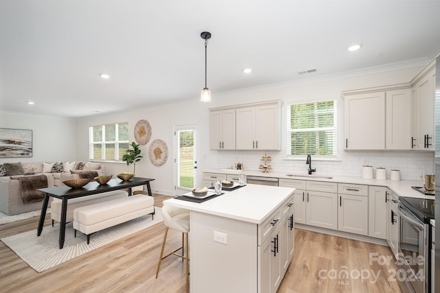 kitchen featuring appliances with stainless steel finishes, light hardwood / wood-style floors, white cabinetry, sink, and hanging light fixtures