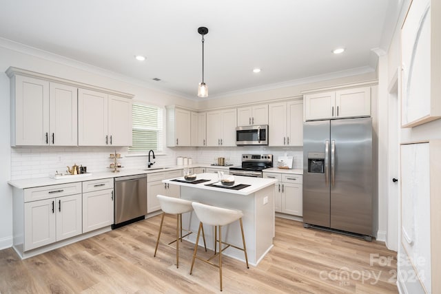 kitchen featuring pendant lighting, stainless steel appliances, a center island, light wood-type flooring, and sink