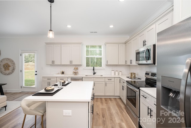 kitchen with sink, hanging light fixtures, light hardwood / wood-style flooring, stainless steel appliances, and a center island