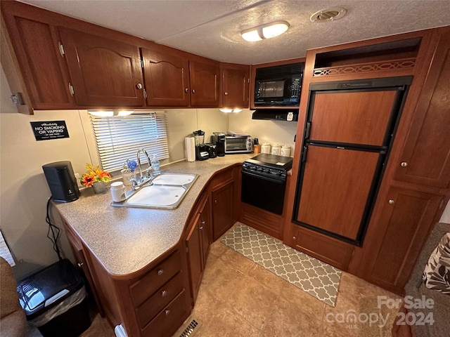 kitchen with light tile floors, black appliances, and sink