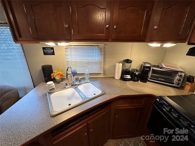 kitchen featuring dark brown cabinets, tile flooring, sink, and black range oven