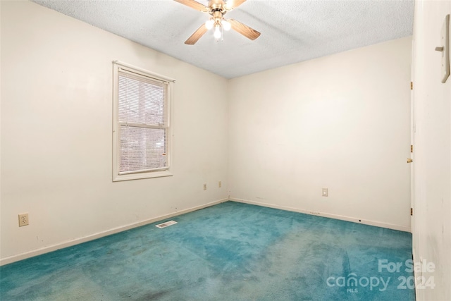 unfurnished room featuring a textured ceiling, dark carpet, and ceiling fan