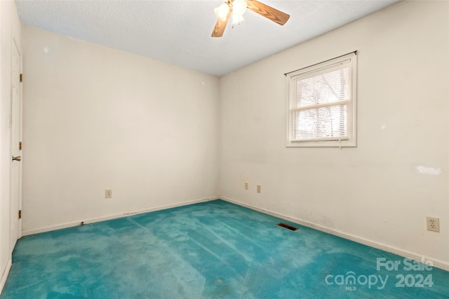 spare room featuring a textured ceiling, carpet floors, and ceiling fan