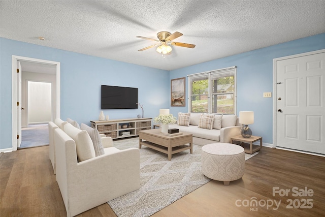living area featuring wood finished floors, a textured ceiling, baseboards, and ceiling fan